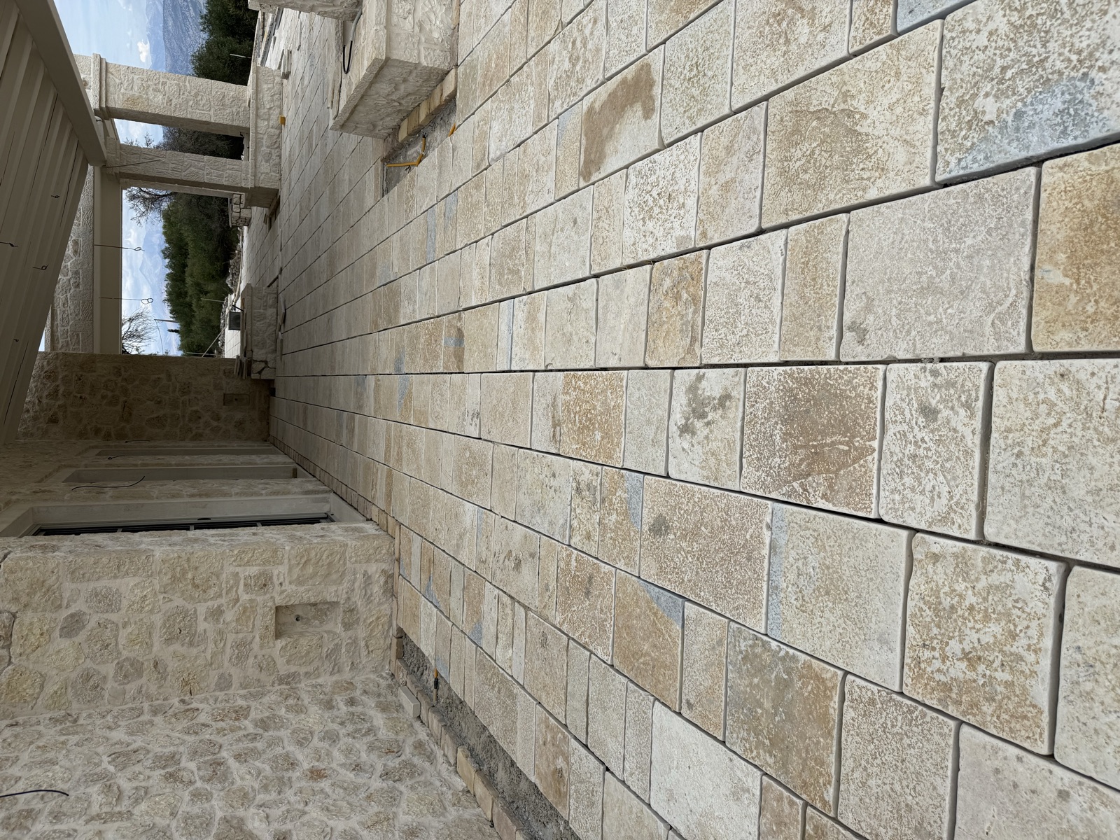 A close view of dressed ashlar limestone blocks meeting cobble paving in a side passage.